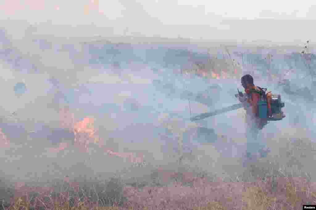 A man attempts to extinguish flames following a rocket attack from Lebanon, amid cross-border hostilities between Hezbollah and Israel, in the Israeli-occupied Golan Heights.
