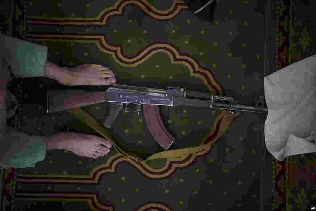 A Taliban fighter lays his AK-47 rifle down during Friday prayers at a Mosque in Kabul, Afghanistan.