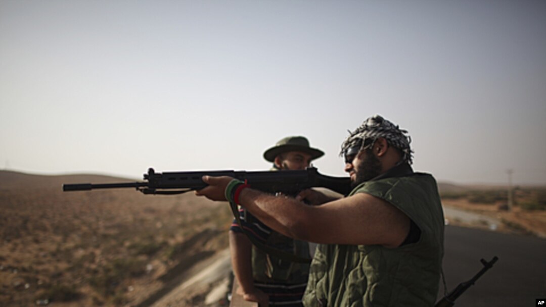 A rebel fighter checks a rifle at a checkpoint between Tarhouna and Bani Walid. Moammar Gadhafi is determined to fight his way back to power, the toppled dictator's spokesman said but a large convoy of his soldiers has apparently deserted, crossing the Li