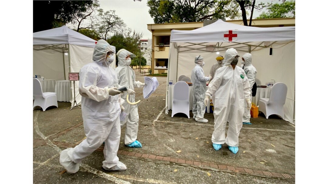 Health workers walk through the grounds at a makeshift COVID-19 testing facility in Hanoi, Vietnam, March 31, 2020.