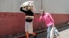 FILE - A woman walks with her blind husband as they carry food collected during a food distribution leaded by the international NGO Gift to the Givers, in Johannesburg, South Africa, Oct. 14, 2020.