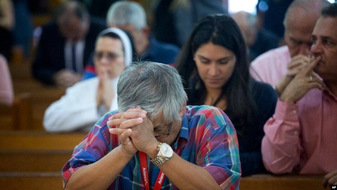 FILE - People pray as the church discuss the Supreme Court hearing arguments regarding the U.S. Constitution requiring states to allow same-sex marriages, April 29, 2015 in Miami. On Feb. 12, 2018, a gay schoolteacher has been fired by a Miami Catholic sc