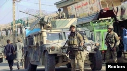 Afghan security forces keep watch in front of their armoured vehicle in Kunduz city, Afghanistan, Oct. 4, 2016. 