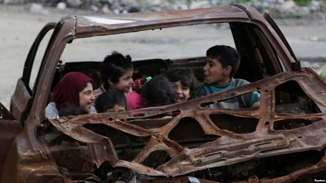 Niños juegan en un carro destrozado en la ciudad de n Aleppo, Syria, Feb. 16, 2015. 