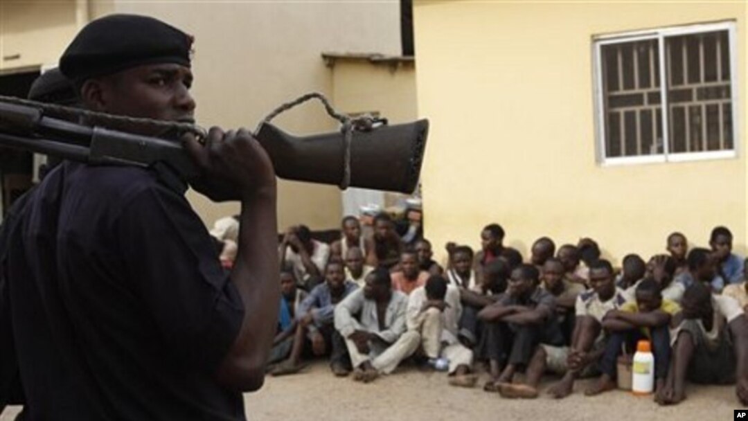 Policeman stand guard as suspected rioters await a court hearing in Kaduna, Nigeria, April 20, 2011