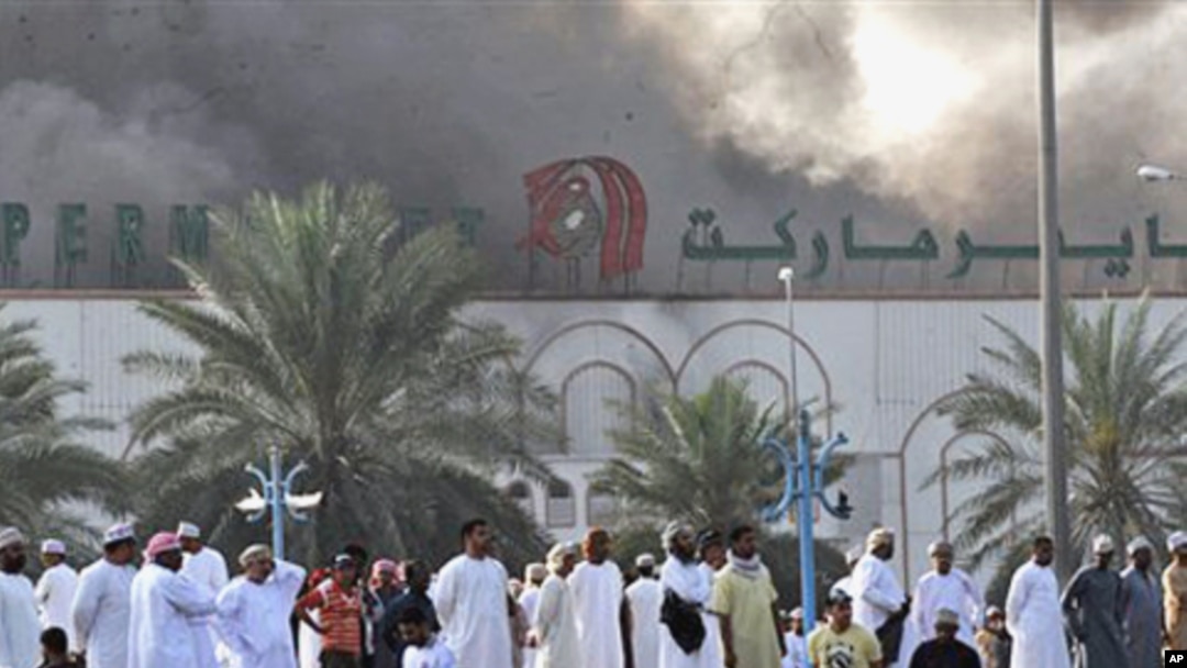 Omani nationals watch smoke rise from Lulu hypermarket in Sohar, February 28, 2011