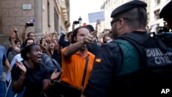 Demonstrators react as they try to stop the car carrying Xavier Puig, a senior at the Department of External Affairs, Institutional Relations and Transparency of the Catalan Government office, after he was arrested by Guardia Civil officers in Barcelona, Spain, Sept. 20, 2017.