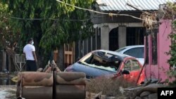 A man looks on near a destroyed car and sofas covered in mud after the passage of Hurricane Eta, since downgraded to Tropical Storm, in Planeta, municipality of La Lima, in the Honduran department of Cortes, on Nov. 9, 2020. 