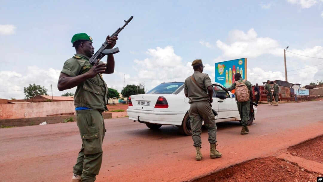 Malian soldiers check a vehicle in the garrison town of Kati, Aug. 18, 2020.