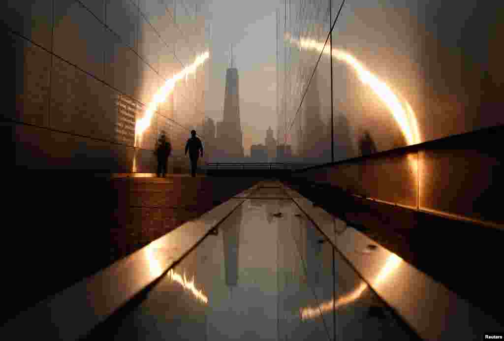 A man walks through the Empty Sky memorial at sunrise across from New York's Lower Manhattan and One World Trade Center in Liberty State Park in Jersey City, New Jersey, Sept. 11, 2013. 