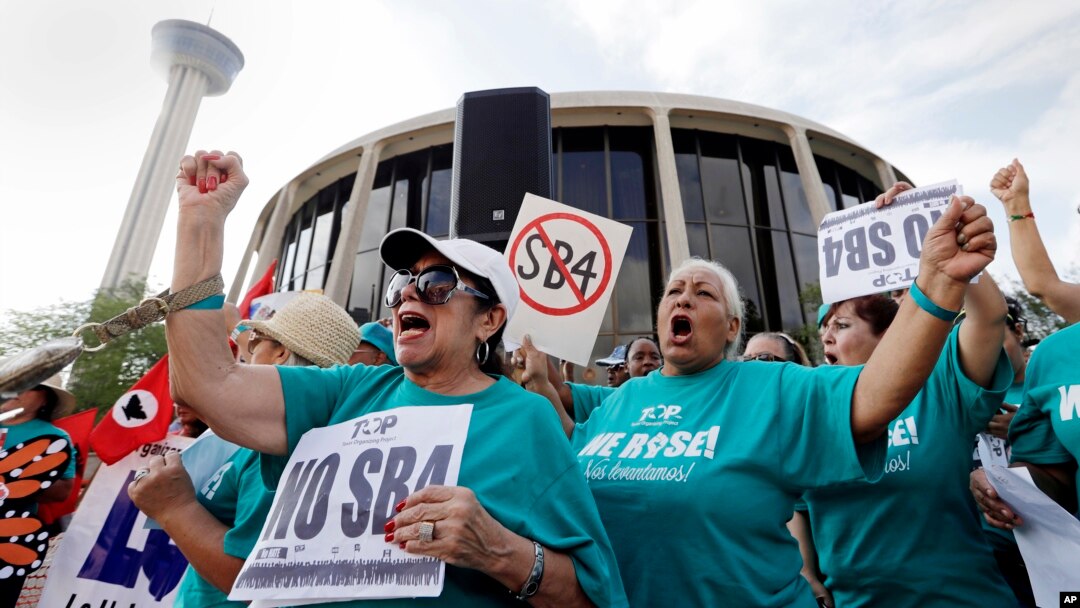 FILE - Lydia Balderas, left, and Merced Leyua, right, join others as they protest against a new sanctuary cities bill outside the federal courthouse in San Antonio, June 26, 2017. 