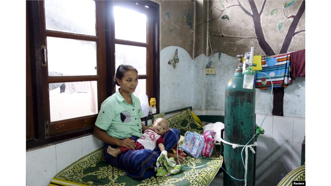 FILE - A refugee from Myanmar sits with her sick child at the Mae Tao clinic in the bordering town of Mae Sot, Oct. 30, 2015. Migrants have mixed emotions over Myanmar's election - hope that a hated government will be defeated, and fear of the uncertain future such an upheaval might bring.