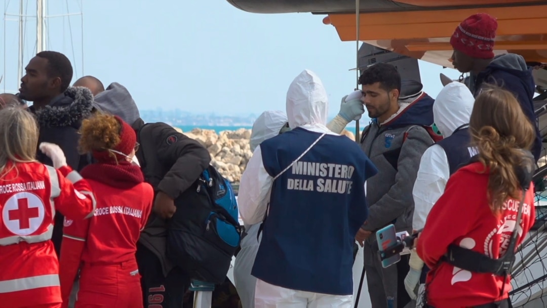 Un funcionario médico con un traje de protección debido al brote de coronavirus, verifica la temperatura de un migrante que desembarca del barco de rescate 'Open Arms' en Pozzallo, Italia, el 2 de febrero de 2020.