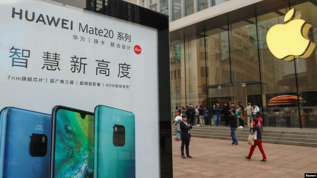 中國上海的Apple商店外面，顧客排隊購買新的iPhone XR手機，附近有華為Mate 20系列產品的廣告（2018年10月26日）