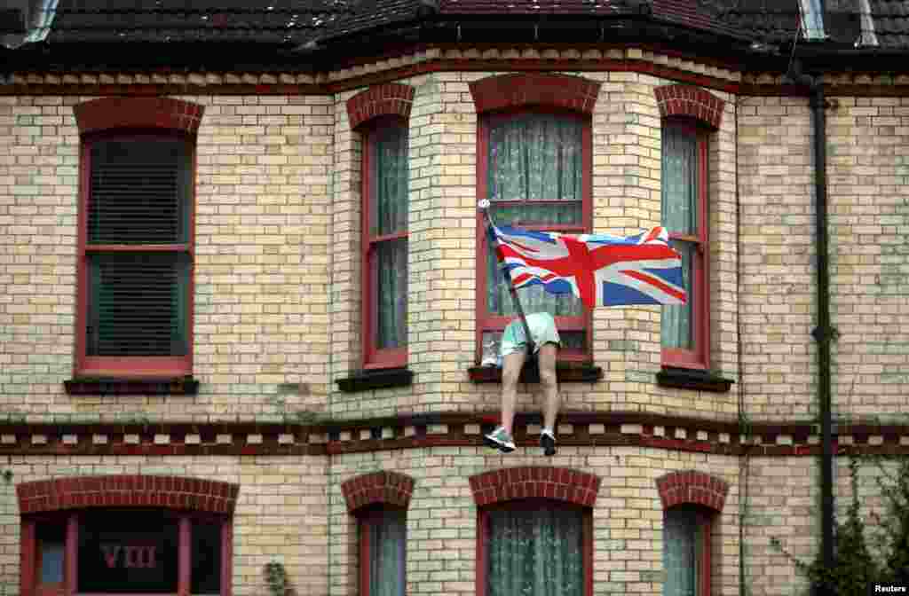 The legs of a mannequin hang out of the window of a house on a residential street in Brighton, Britain.