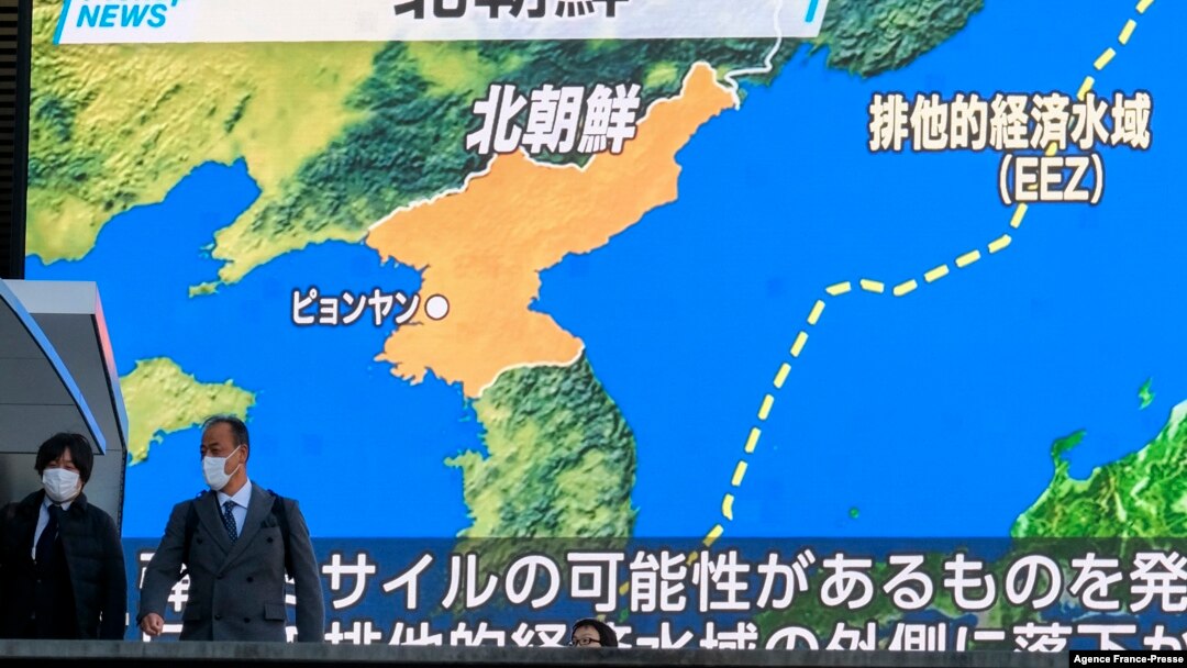 Pedestrians walk past a screen displaying a map after North Korea fired a missile into the sea off its east coast according to South Korea and Japan, during a news broadcast at Akihabara district in Tokyo, Jan. 5, 2022.
