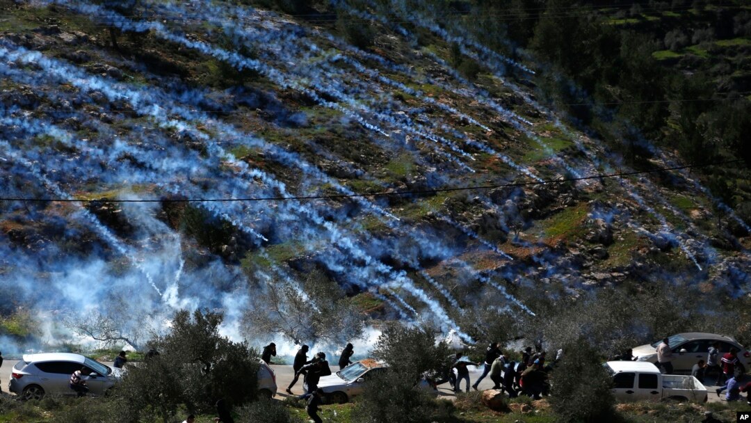 FILE - Palestinian demonstrators run away from tear gas fired by Israeli forces during a protest against Israeli settlements and U.S. President Donald Trump's Mideast initiative, in the West Bank village of Beita near Nablus, Feb. 28, 2020.