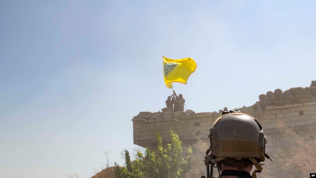 FILE - A U.S. soldier oversees members of the Syrian Democratic Forces as they demolish a Kurdish fighters' fortification and raise a Tal Abyad Military Council flag over the outpost as part of the "safe zone" near the Turkish border, Sept. 21, 2019.