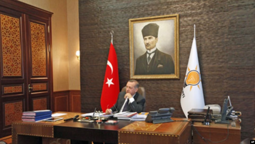Turkey's Prime Minister Tayyip Erdogan, with a portrait of modern Turkey's founder Ataturk in the background, watches TV at his office at the AK Party headquarters in Ankara, Turkey, June 13, 2011 (file photo)