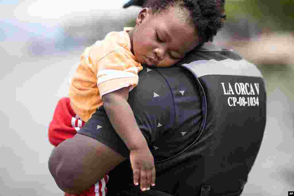 Un migrante haitiano sostiene a su hijo antes de abordar un bote hacia Capurgan&#225;.