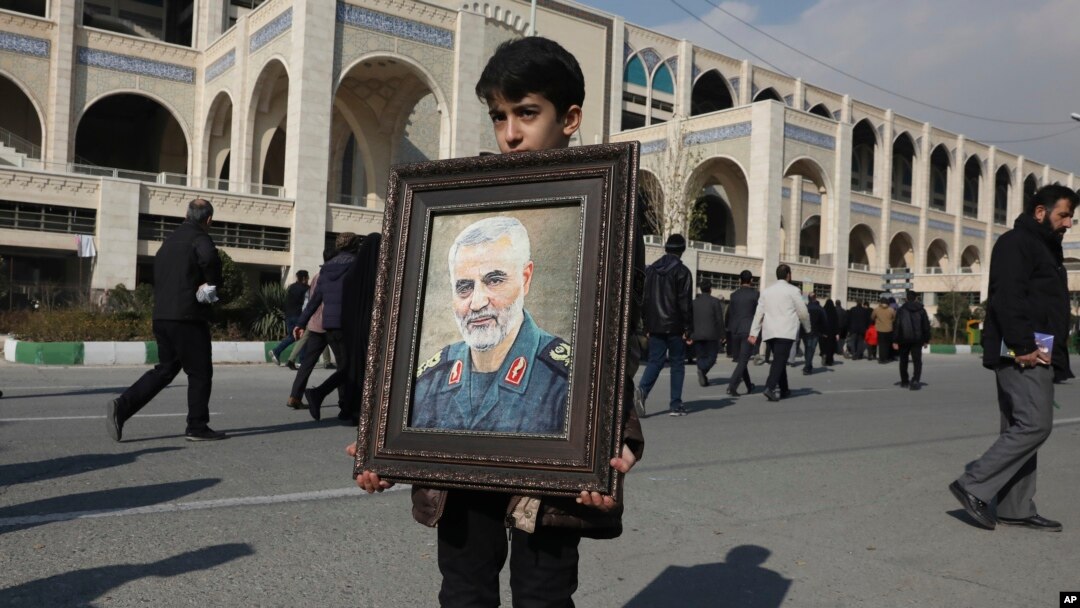 A boy carries a portrait of Iranian Revolutionary Guard Gen. Qassem Soleimani before Friday prayers in Tehran, Jan. 3, 2020. Iran has vowed "harsh retaliation" for the U.S. airstrike near Baghdad's airport that killed Tehran's top general.
