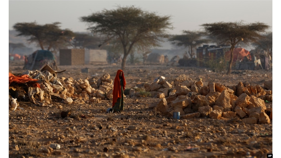 A Somali woman walks through a camp of people displaced from their homes elsewhere in the country by the drought, shortly after dawn in Qardho, Somalia, March 9, 2017.