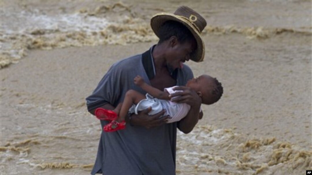 A man carries a child while wading across a flooded street during the passing of Hurricane Tomas in Leogane, Haiti, 05 Nov 2010