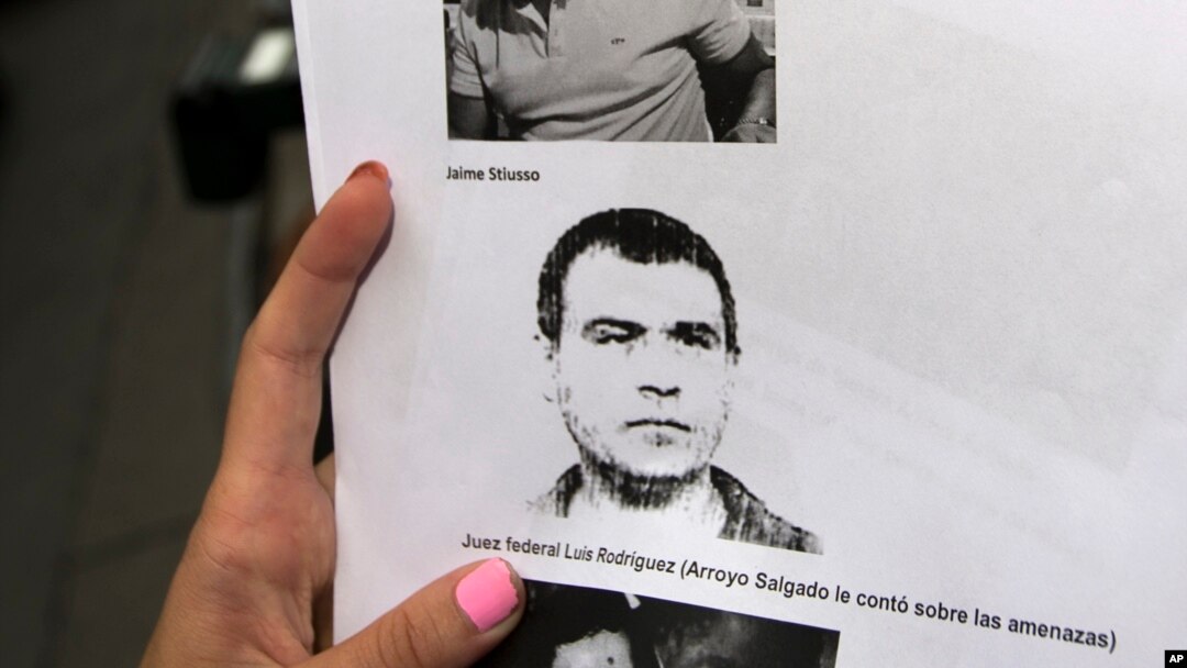 FILE - A reporter holds an image of Antonio Stiusso, former Argentine spy chief, who left the country last week after making a statement to the prosecutor investigating Alberto Nisman's death.