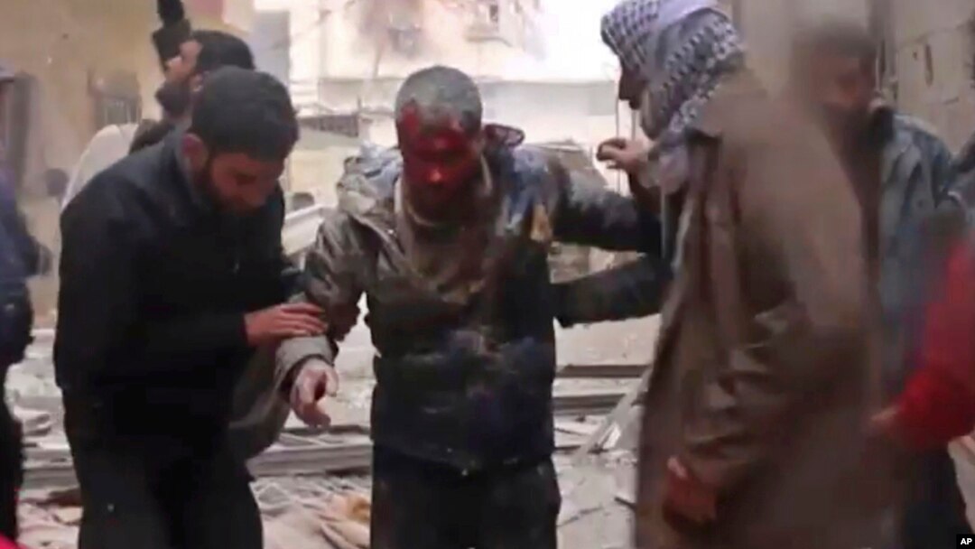 In this frame grab from video released Jan. 1, 2018 by the Syrian Civil Defense group, known as the White Helmets, Syrians help an injured man on a stretcher after an airstrike hit the Damascus suburb of Masraba, Syria.