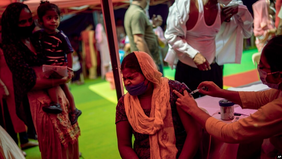 In this Wednesday, Sept. 29, 2021 file photo, a woman reacts as a health worker inoculates her during a vaccination drive against COVID-19 in New Delhi, India. (AP Photo/Altaf Qadri, file)