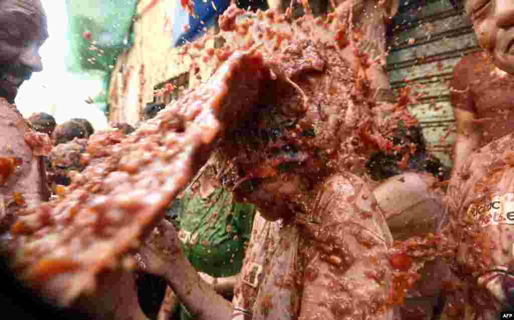 A reveler is pelted with smashed tomatoes puree, during the 'Tomatina' festival in Bunol, Spain.