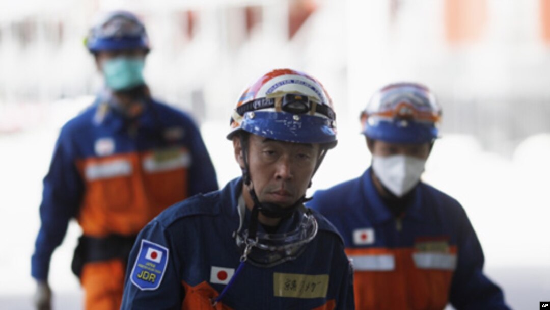 Japanese rescue workers walk past the rubble of the CTV building that houses an English language school in Christchurch, New Zealand, Feb. 24, 2011.