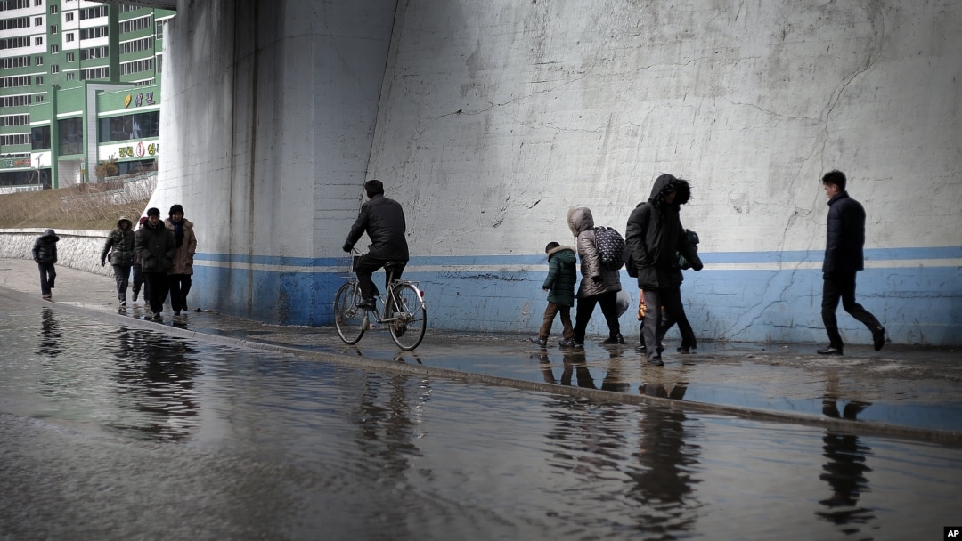 FILE - North Koreans walk along a flooded street.