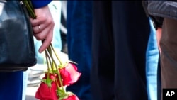 In this grab taken from footage provided by the Russian State Atomic Energy Corporation ROSATOM press service, a woman holds roses as people gather for the funerals of five Russian nuclear engineers killed by a rocket explosion in Sarov, Aug. 12, 2019.