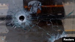 Impactos de bala se observan en la ventana de una pizzería donde desconocidos armados mataron a cuatro empleados de una emisora radial en Ciudad Juárez, México, el 11 de agosto de 2022. Foto Reuters.