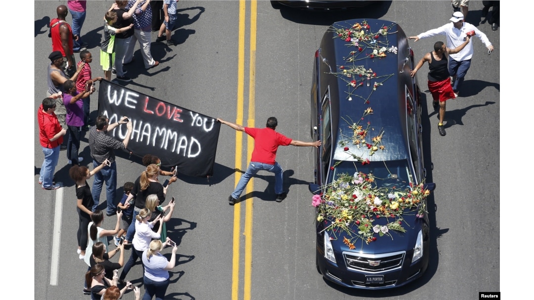 A well-wisher holding a banner touches hearse carrying remains of Muhammad Ali during funeral procession for the three-time heavyweight boxing champion in Louisville, Kentucky, June 10, 2016.