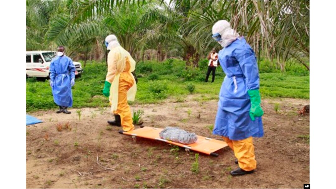 FILE - In this photo taken on Friday, June 19, 2015, the wrapped remains of a new born child suspected of contracting the Ebola virus, lays on a stretcher as health workers, dressed in Ebola protective gear, move the body for burial in Dubreka, Guinea.