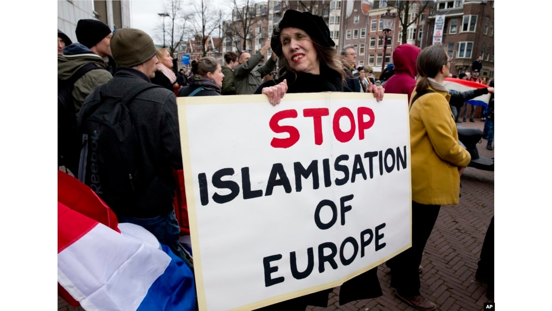 FILE - A woman holds a placard at a rally calling against immigration and what demonstrators see as the Islamization of their communities, in Amsterdam, Netherlands, Feb. 6, 2016.