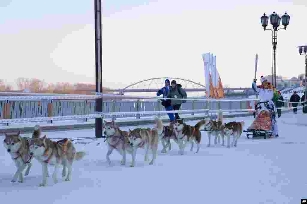 Torch bearer Mikhail Fateyev dogsleds with an Olympic torch on the embankment of the Tura River during the Olympic torch relay in Tyumen, western Siberia, Russia. (Photo provided by Olympictorch2014.com)