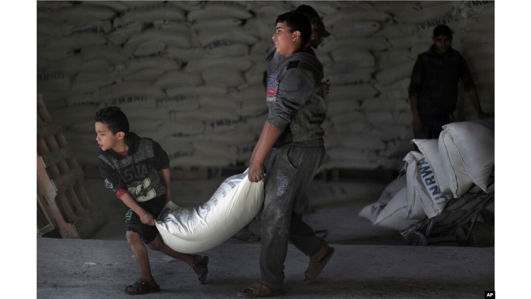FILE - Palestinians receive UNRWA food aid at a U.N. warehouse at Shati refugee camp, in Gaza City, Jan. 14, 2018.