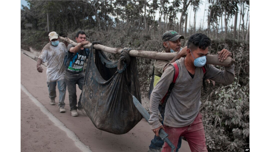 Residents carry a body recovered near the "Volcano of Fire," in Escuintla, Guatemala, June 4, 2018.
