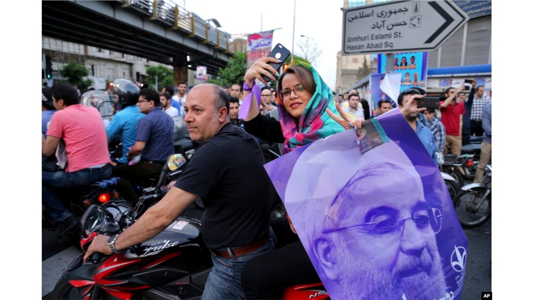 A supporter of Iran's President Hassan Rouhani, who is running for a second term in office, holds his poster during a campaign rally in downtown Tehran, May 16, 2017.
