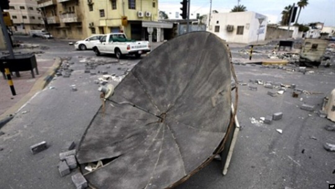 Cars drive past barricades set up by Bahraini demonstrators at a Shiite neighborhood in Manama on March 17, 2011