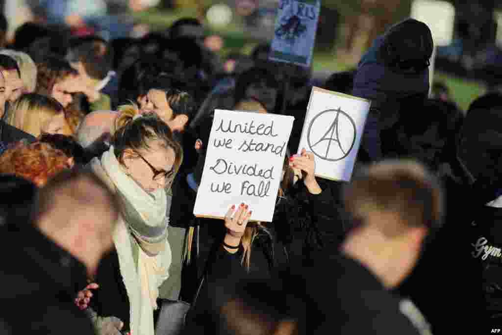 A woman holds the "#PeaceForParis" logo and a placard reading "United we stand, Divided we fall" on Nov. 15, 2015 in Caen during a demonstration in front of the Memorial of Caen in tribute to the victims of the Paris attacks.