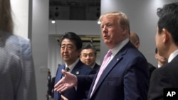 參加大阪20國集團峰會的美國總統特朗普和日本首相安倍晉三走在一起。(2019年6月28日) 