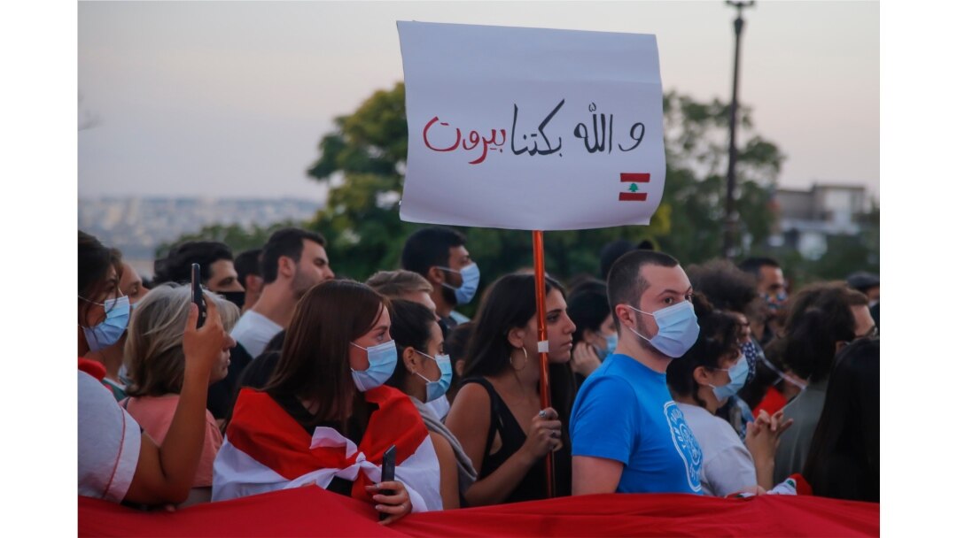 A member of the Lebanese community holds a placard that reads "For Beirut we cry," during a vigil in front of Sacre Coeur Basilica in memory of victims of the deadly blast in Beirut, in Paris, France, Aug. 5, 2020.