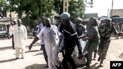 Security forces transport with a blanket the remains of some of the 11 victims of a double blast in the northern Cameroonian city of Maroua, July 22, 2015. 