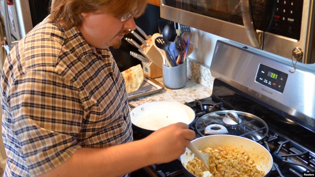 Clint Parry cooks chicken tacos at home for himself and his wife, Amanda, in Auburn Hills, Michigan, U.S., July 30, 2020. Picture taken July 30, 2020. (Amanda Parry/Handout via REUTERS)