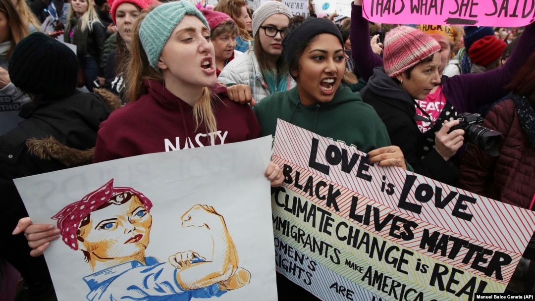 Kaelyn Warne, left, and Marvi Ali both former students of College of William & Mary in Williamsburg, Va., join protest with other women against President Donald Trump.