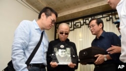 FILE - Liu Xia, wife of jailed Nobel Peace Prize winner and Chinese dissident Liu Xiaobo, holds a portrait of him during his funeral in Shenyang in northeastern China's Liaoning Province, July 15, 2017.